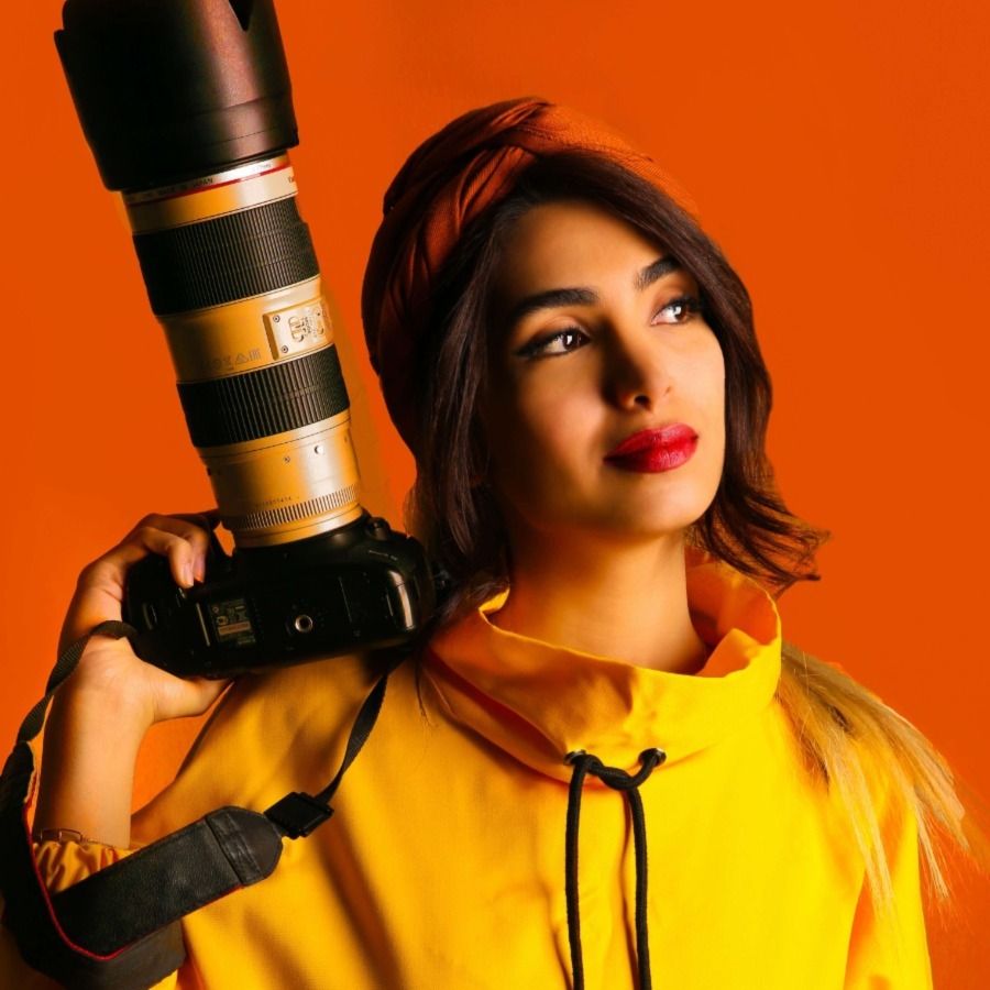 Модный фотограф с камерой на оранжевом фоне